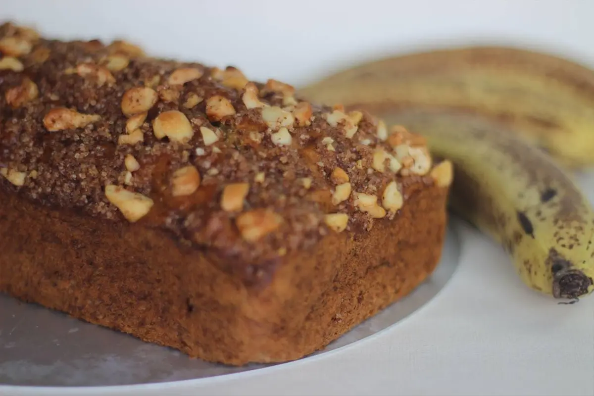 Slicing a loaf of banana bread on a rustic wooden cutting board