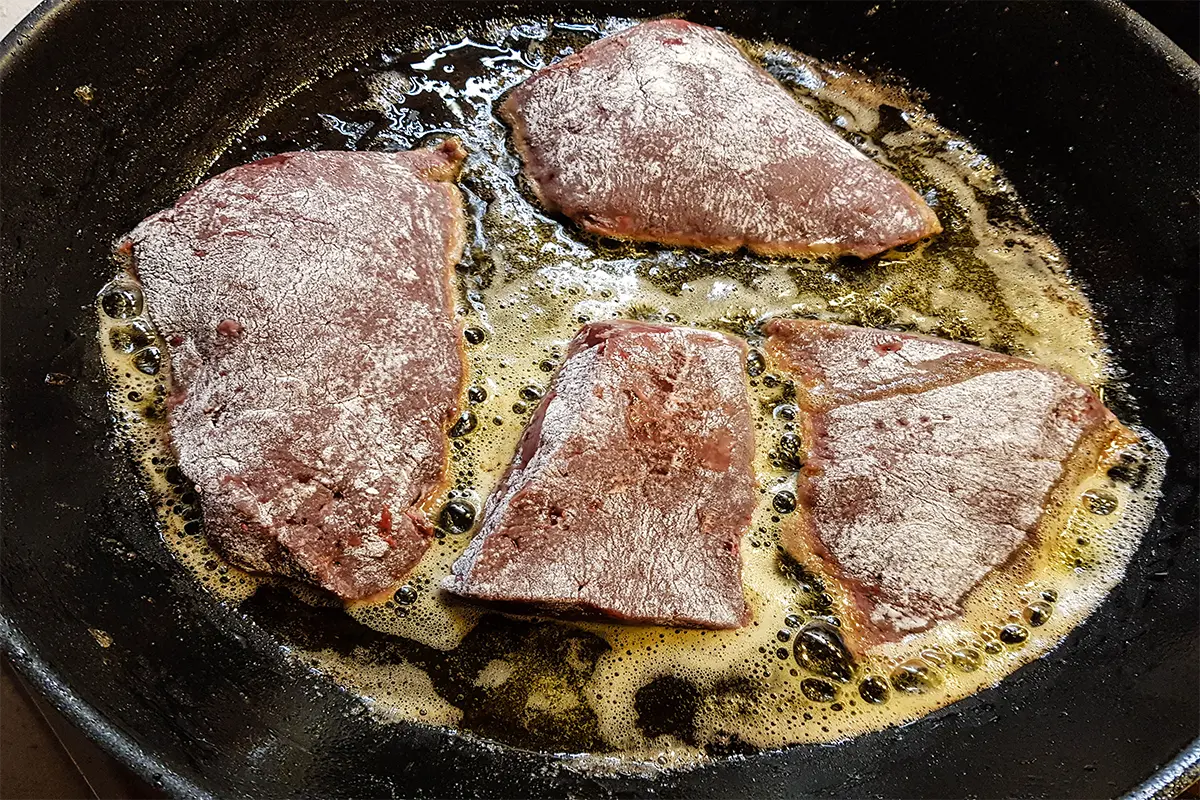 Chef preparing tenderized meat in a professional kitchen